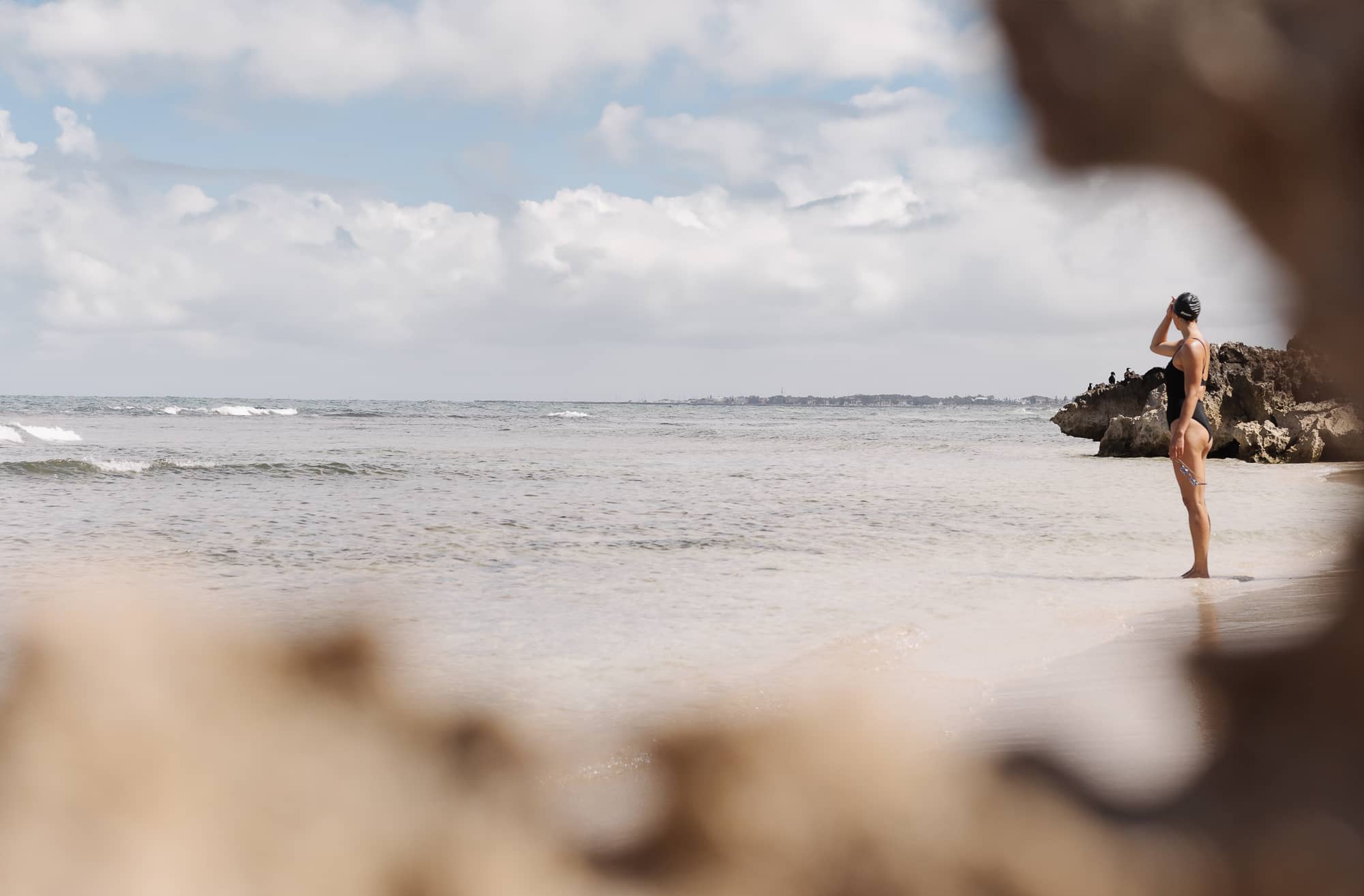 active woman looking out to the ocean wearing the bouncedown one piece