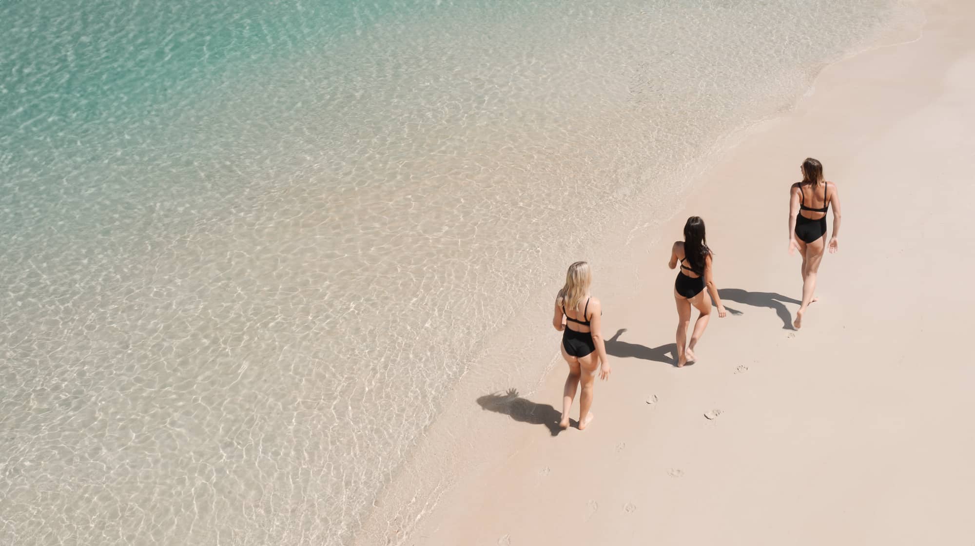 three active women wearing the BounceDown One Piece walking by the ocean